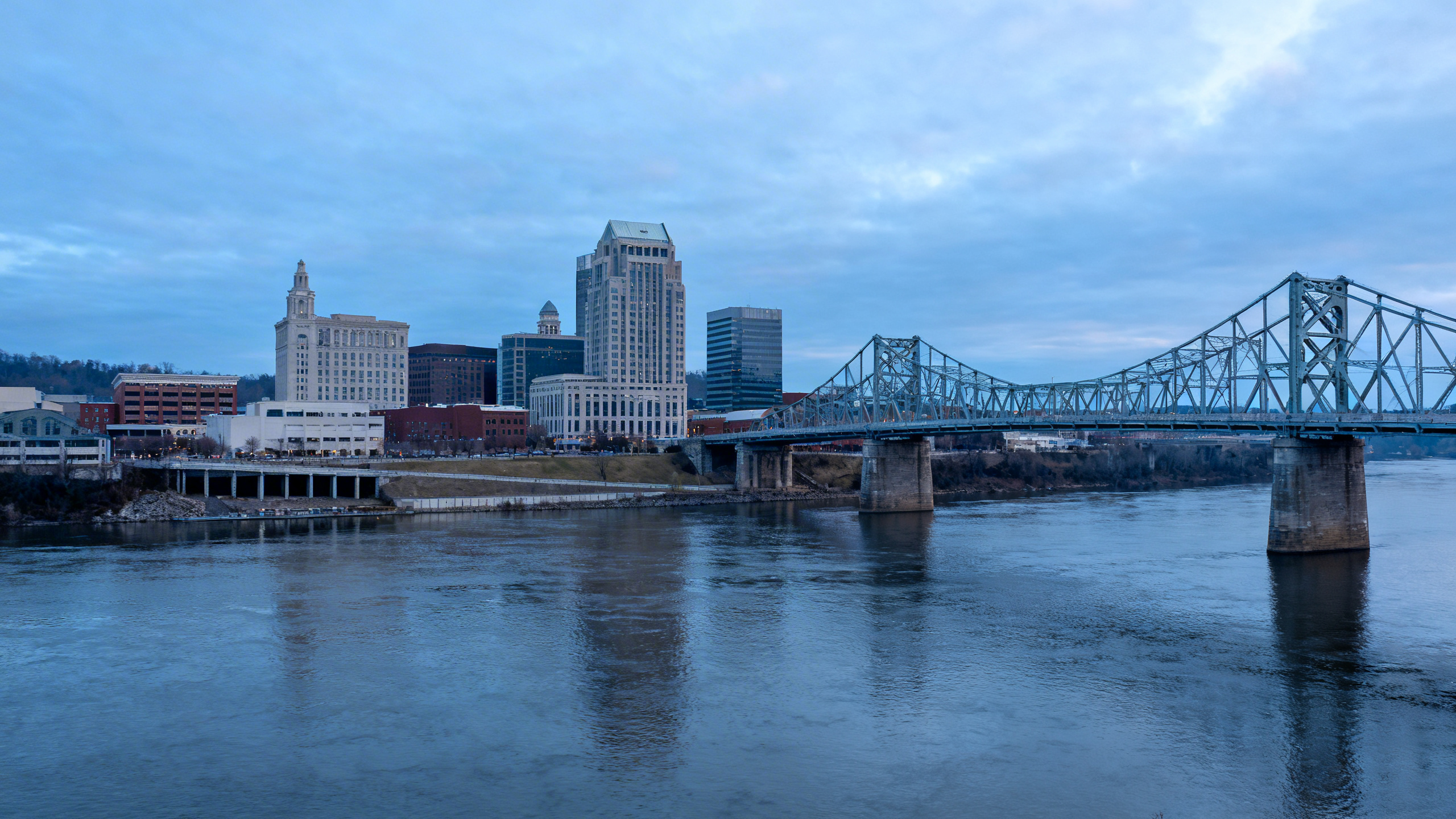 Downtown Chattanooga with the Tennessee River and historic bridges under a cloudy blue sky in the early morning