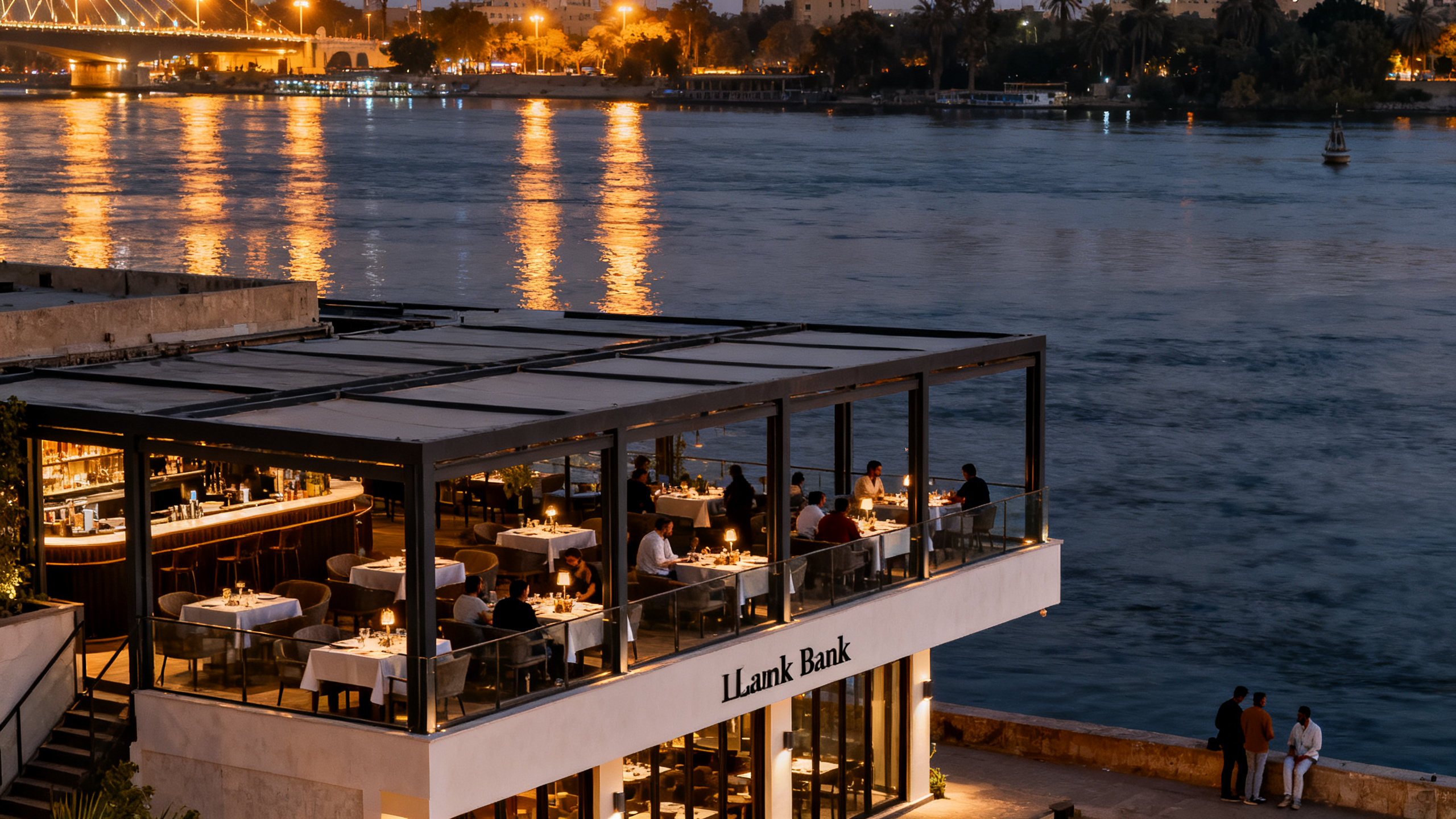 Left Bank restaurant's modern outdoor terrace overlooking the Nile Corniche with lights reflecting on the water at night