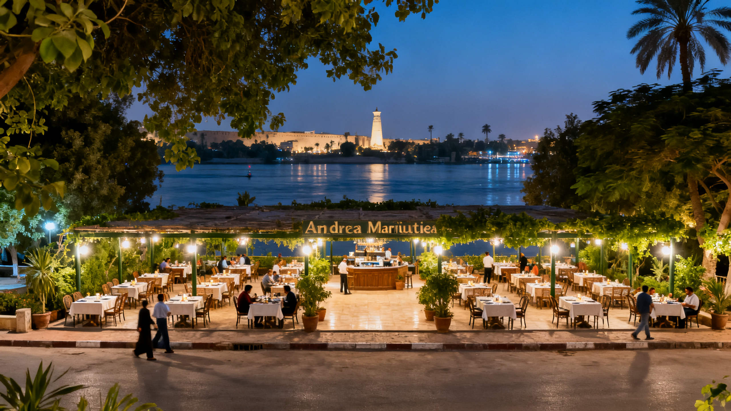 Spacious outdoor dining area of Andrea Mariouteya near the Nile, surrounded by greenery and softly glowing lights under the night sky