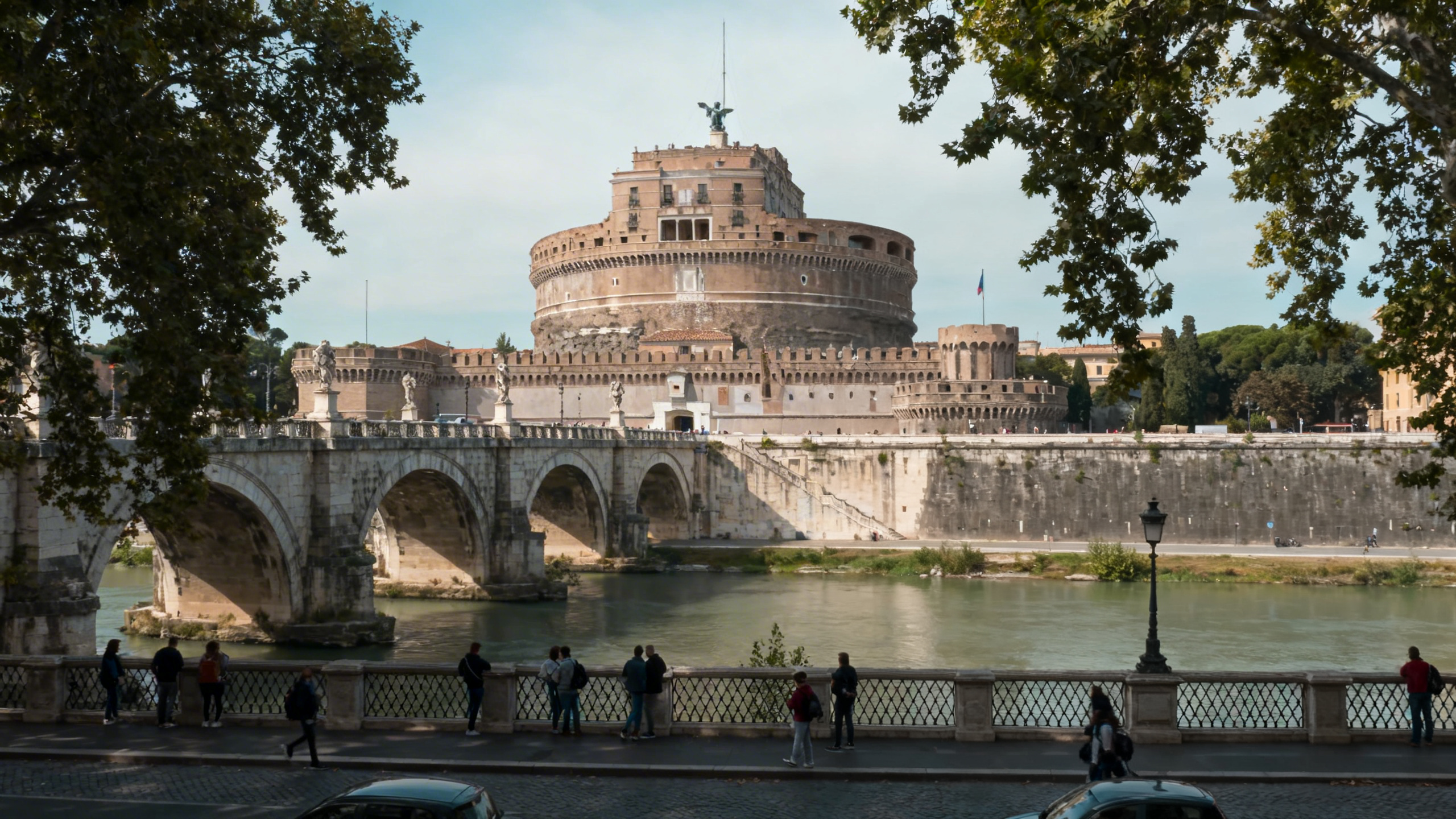The circular fortress of Castel Sant’Angelo standing beside the Tiber River with a stone bridge leading to its entrance