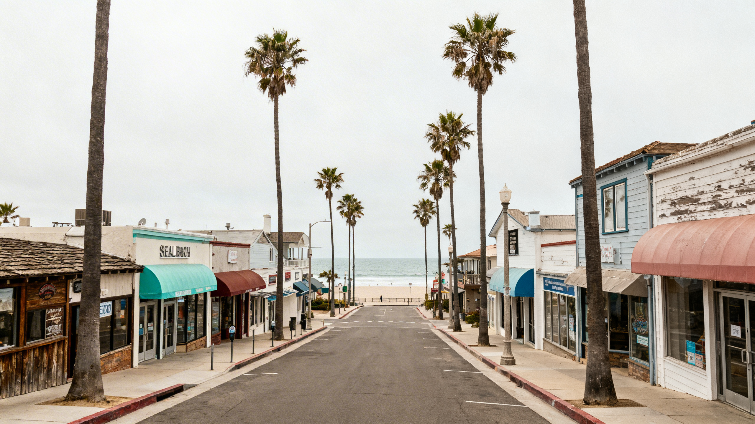 A peaceful beachside town street with palm trees and quaint shops near the ocean at Seal Beach, California