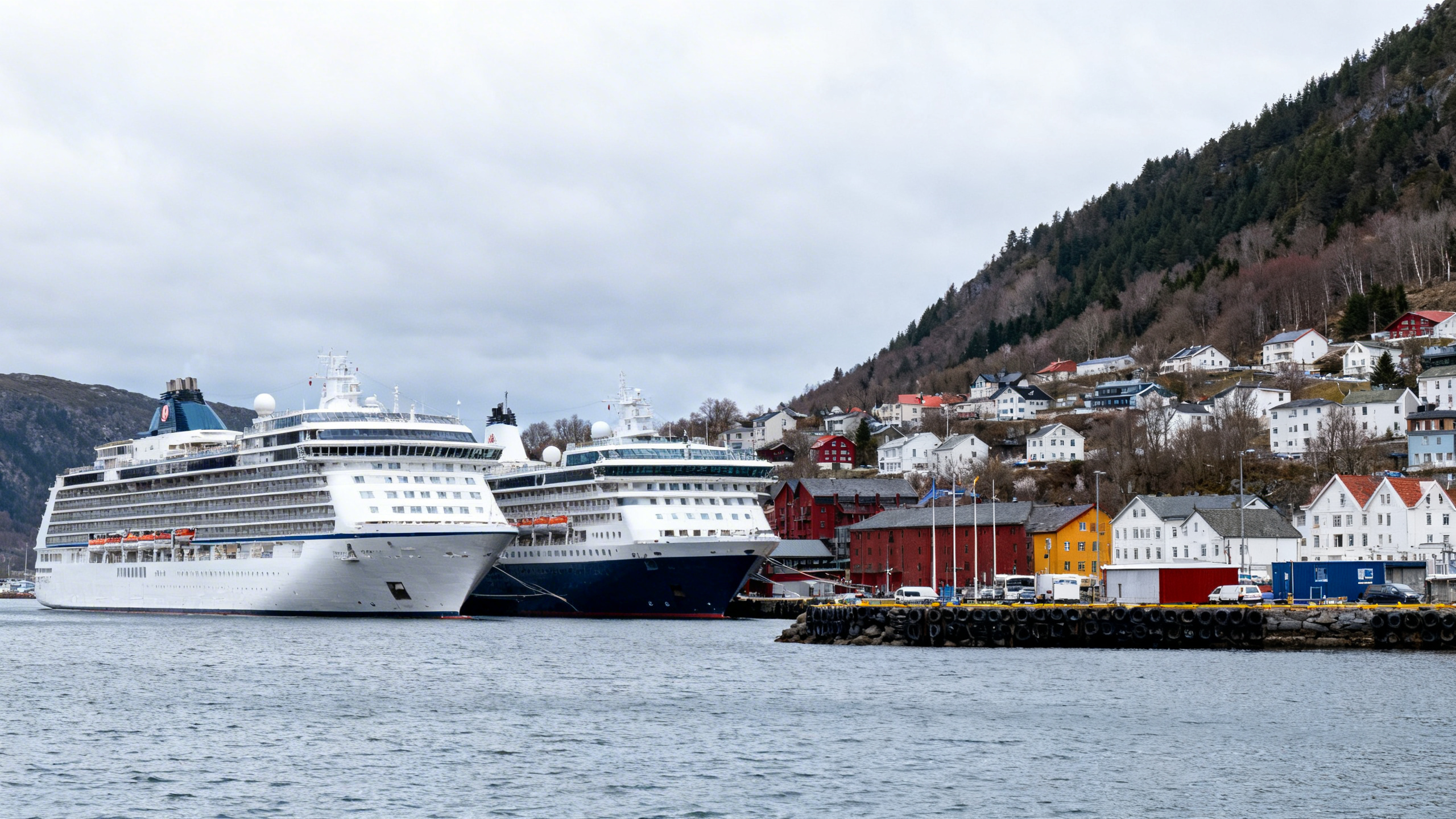 A calm port town with cruise ships docked under an overcast sky during early spring