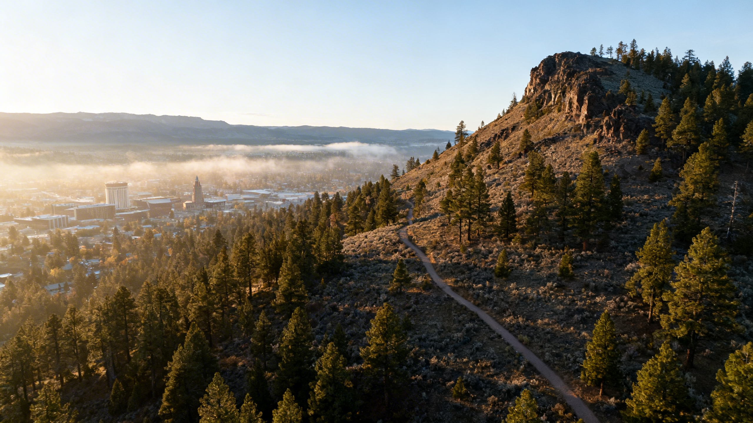 Sunlit view of mountain terrain and pine forests around Bend with clear skies and outdoor trails visible