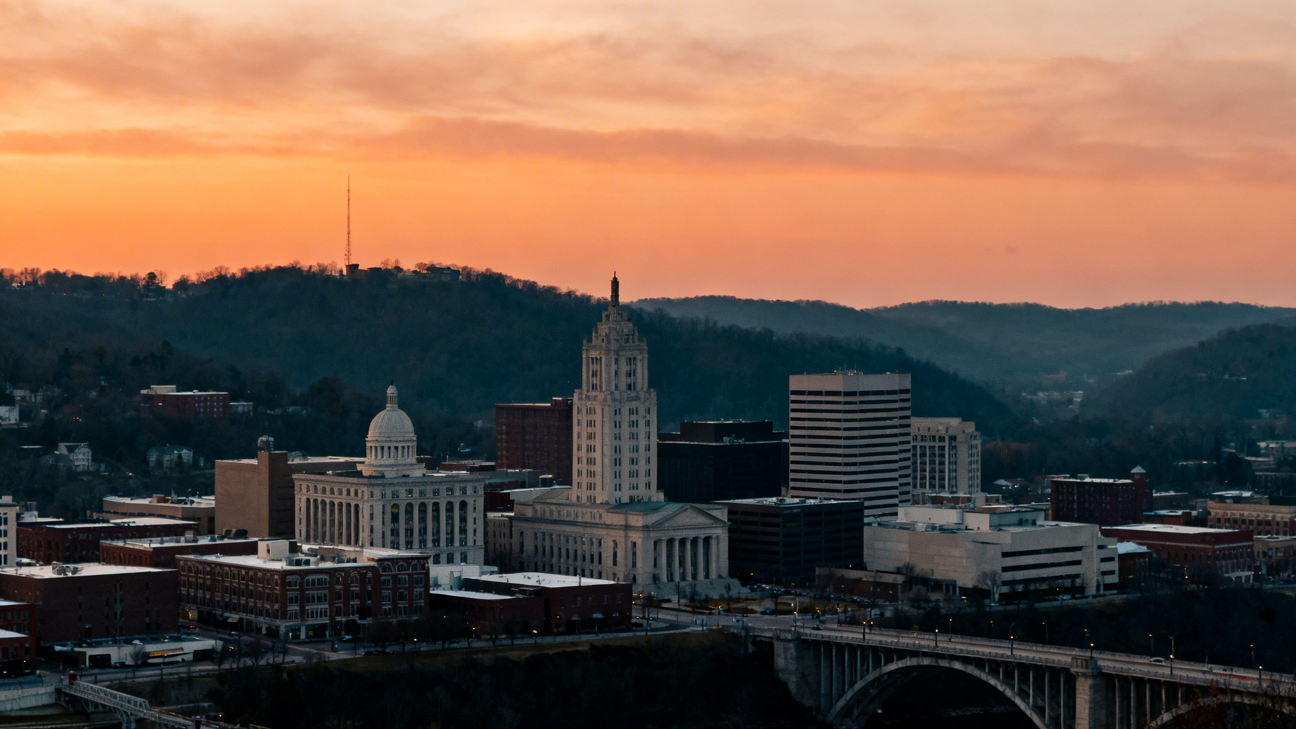 Panoramic view of Knoxville’s downtown skyline and nearby hills during sunset with warm orange hues
