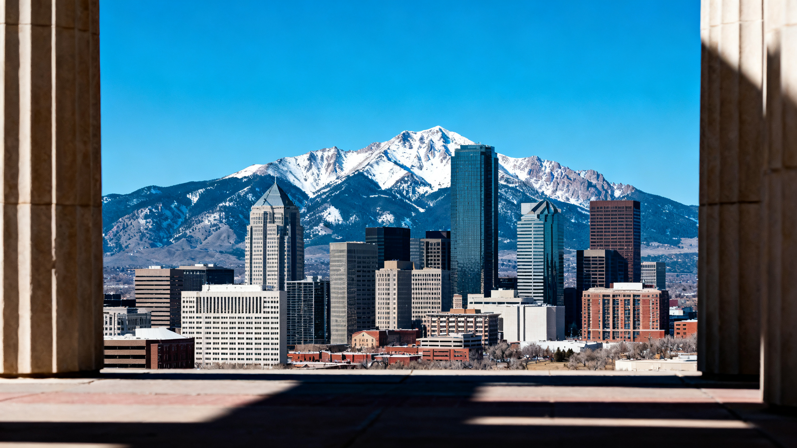 Denver cityscape with the Rocky Mountains rising tall under a clear blue sky in the background