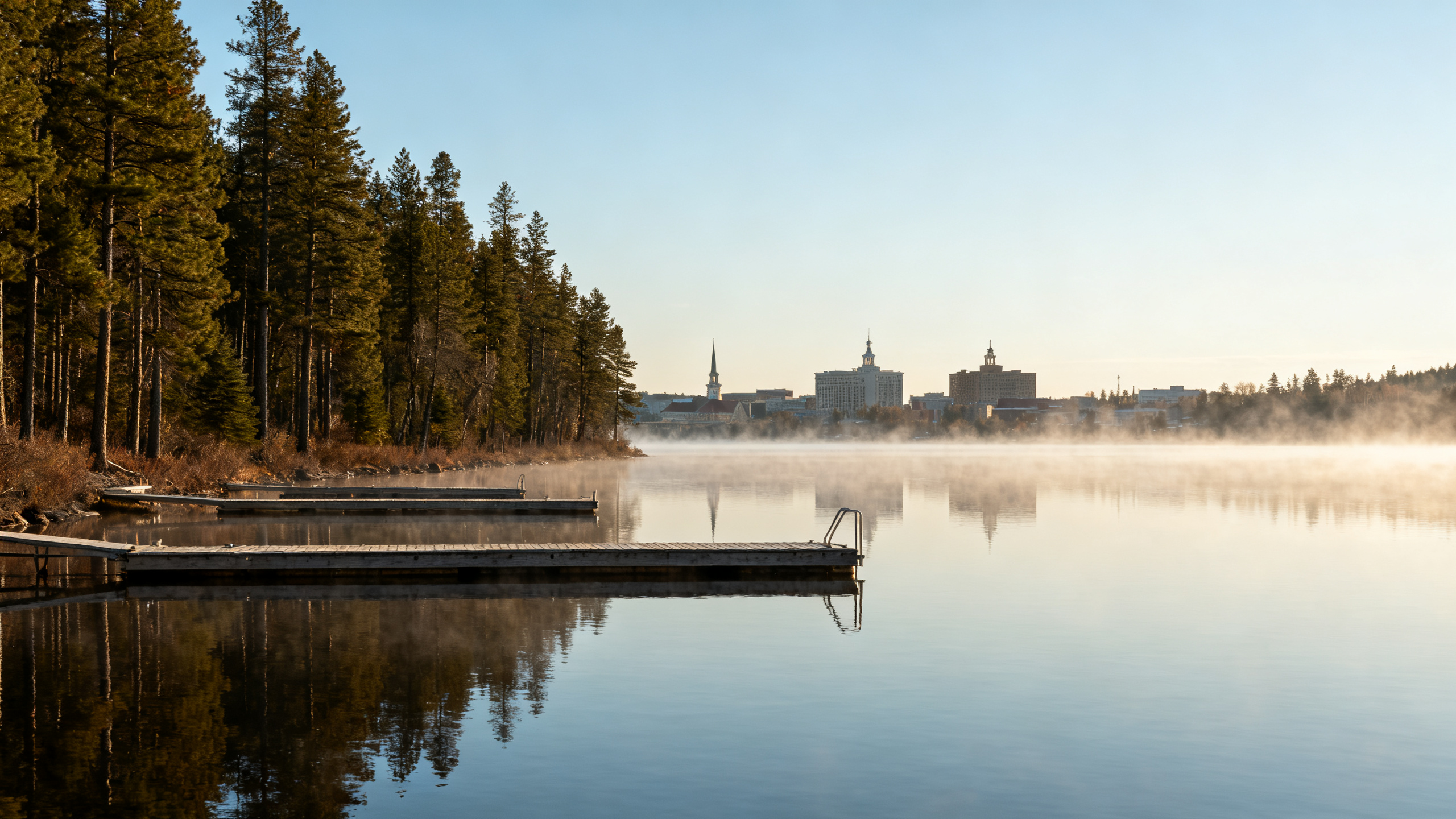 A calm lake with docks and pine forests lining the shore, clear skies above the peaceful Eagle River area.