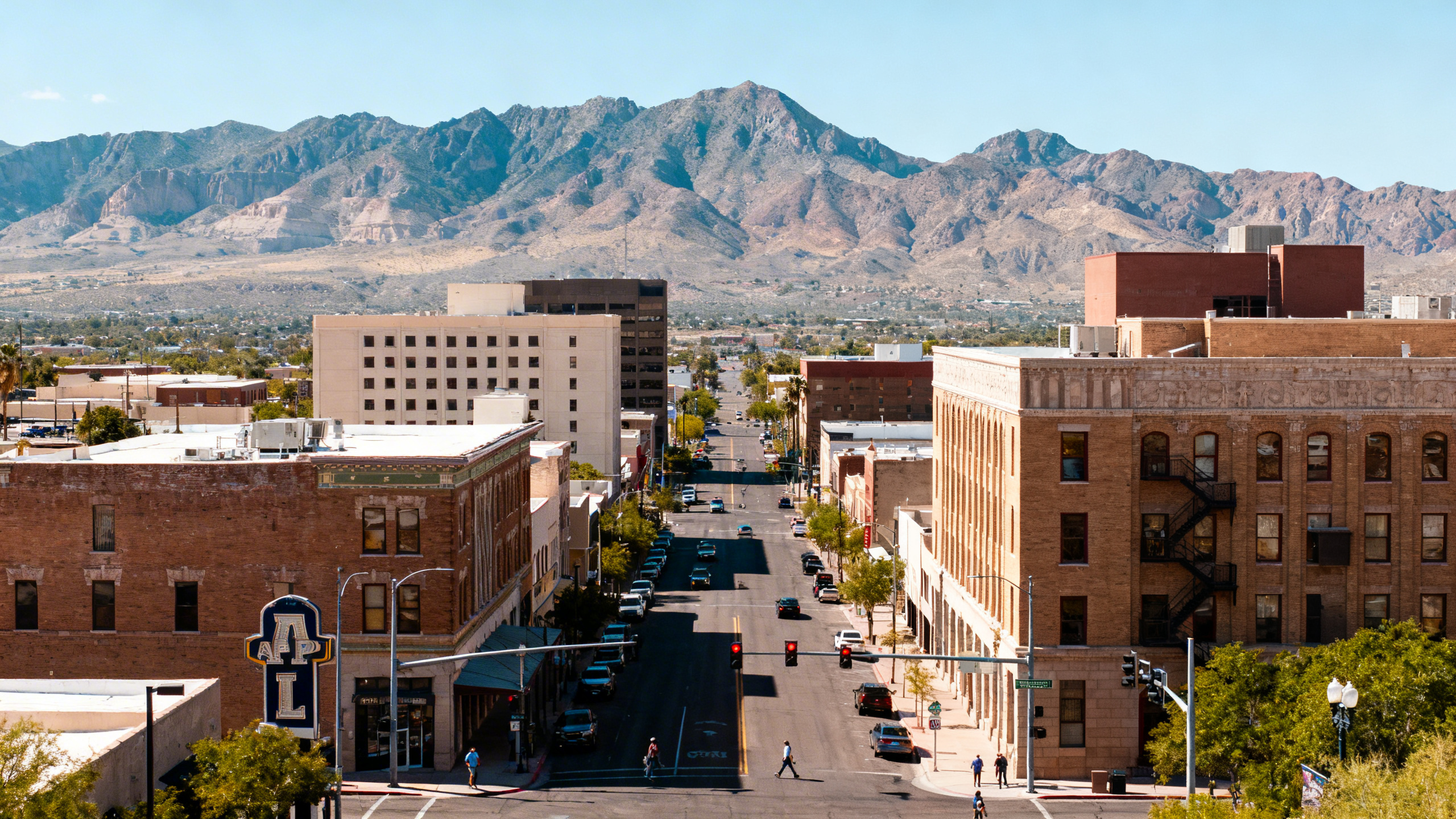 A bustling downtown street with historic buildings and mountain views in the background in El Paso, Texas