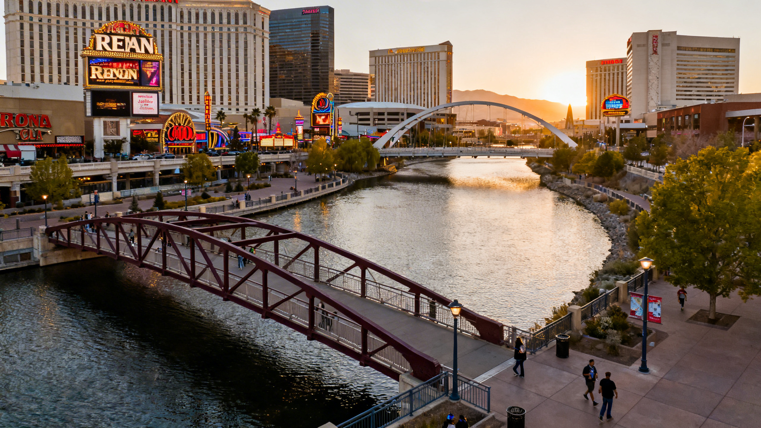 Riverwalk area with casinos and pedestrian bridges along the water in downtown Reno during sunset