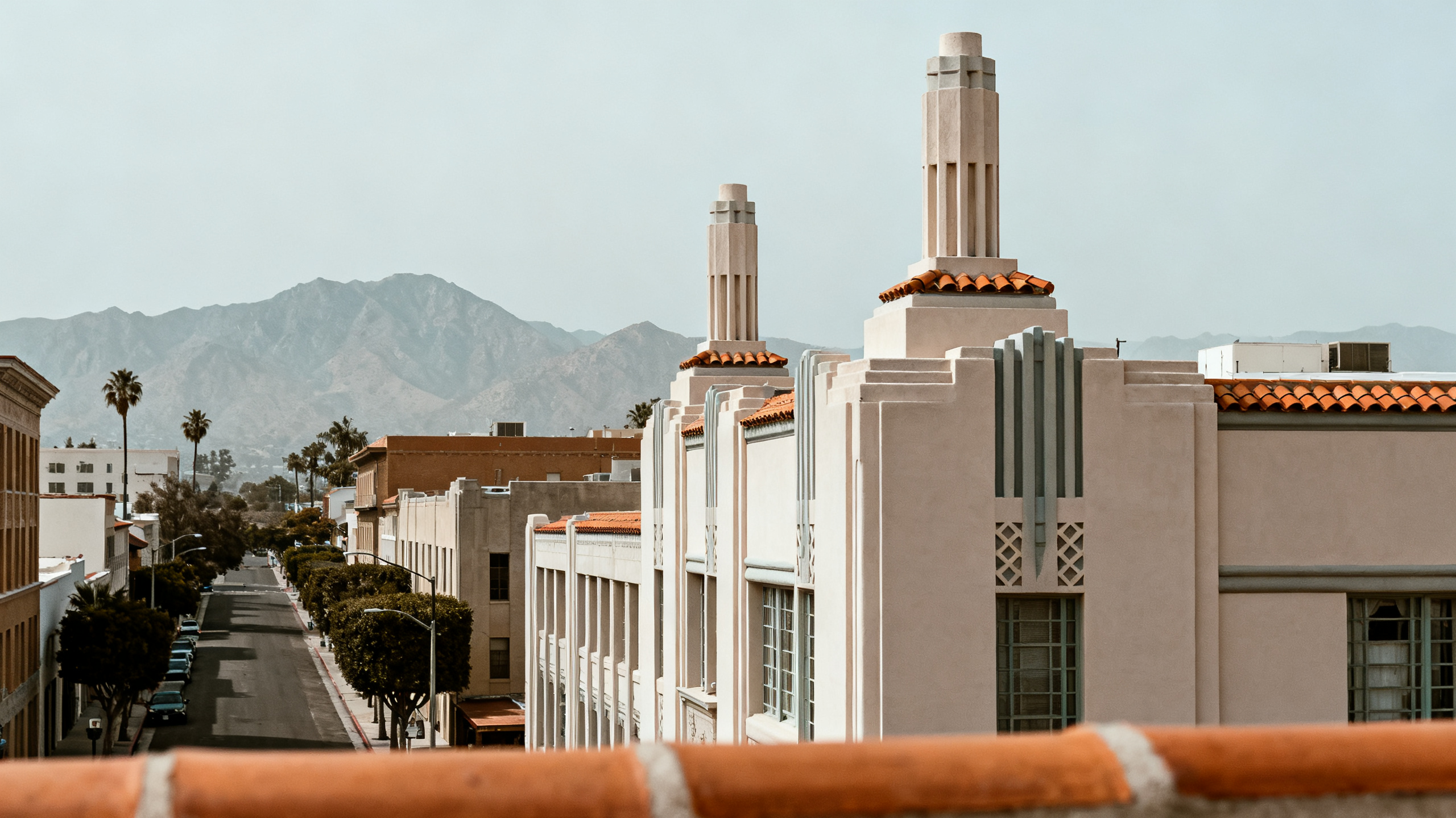 Historic downtown street with art deco buildings and mountain range visible in the distance under a clear sky