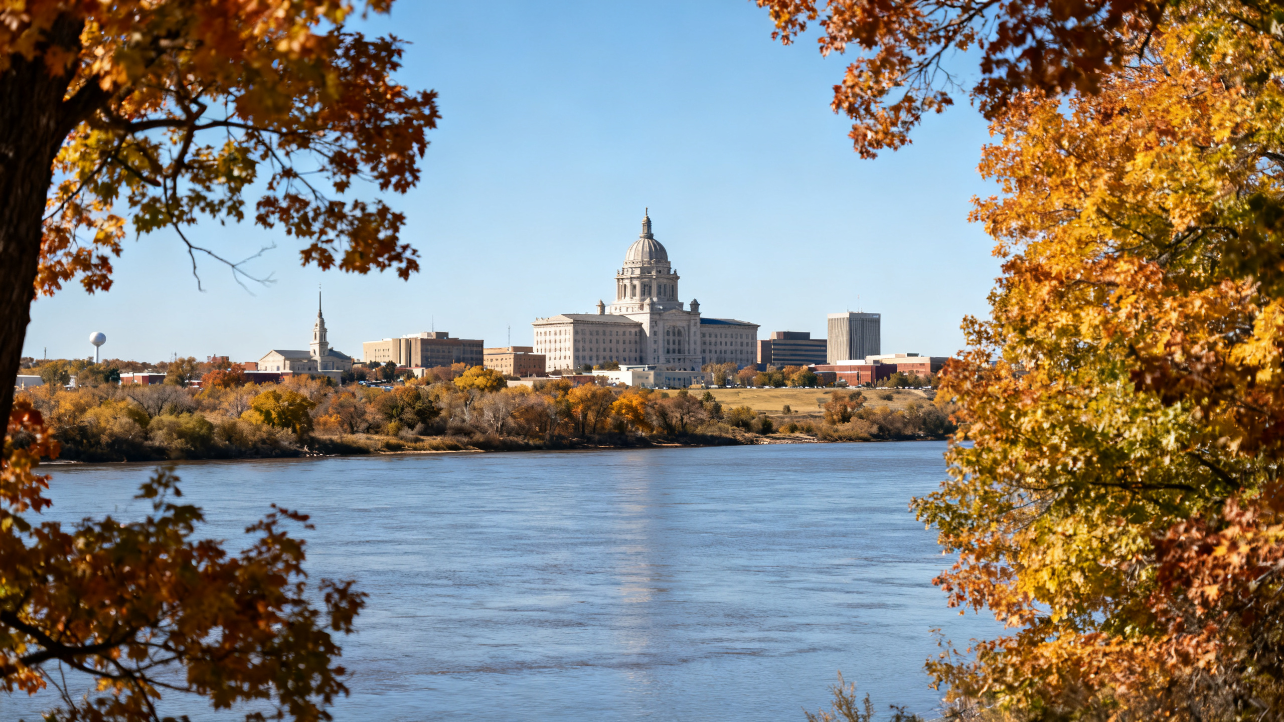 Wide Missouri River with a city skyline in the background, framed by autumn trees in Bismarck
