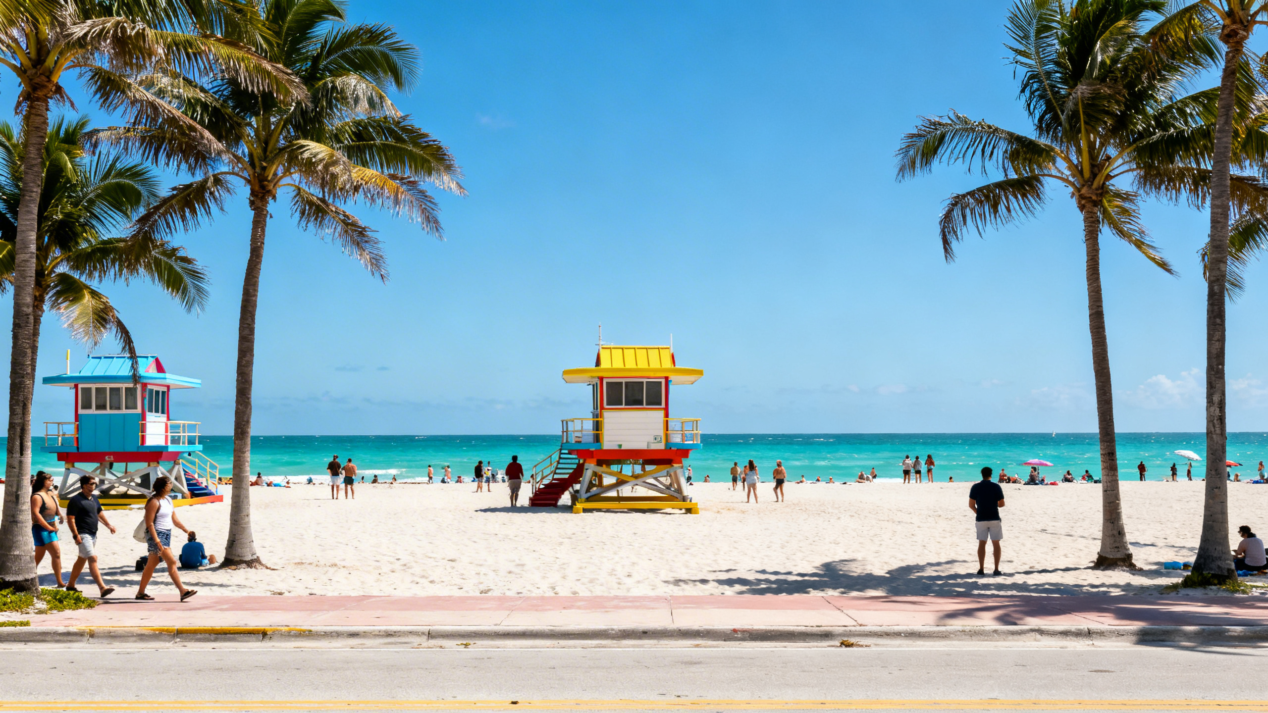 The bustling South Beach shoreline with colorful lifeguard towers and turquoise Atlantic waters under clear blue sky