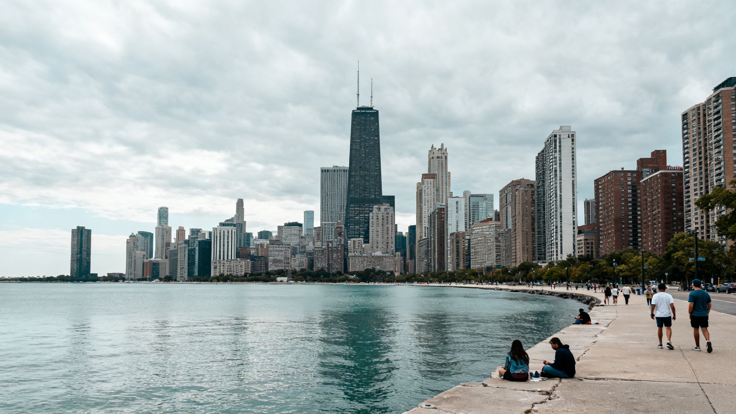 View of Lake Michigan with Chicago’s skyline towering behind, framed by cloudy skies and calm waters
