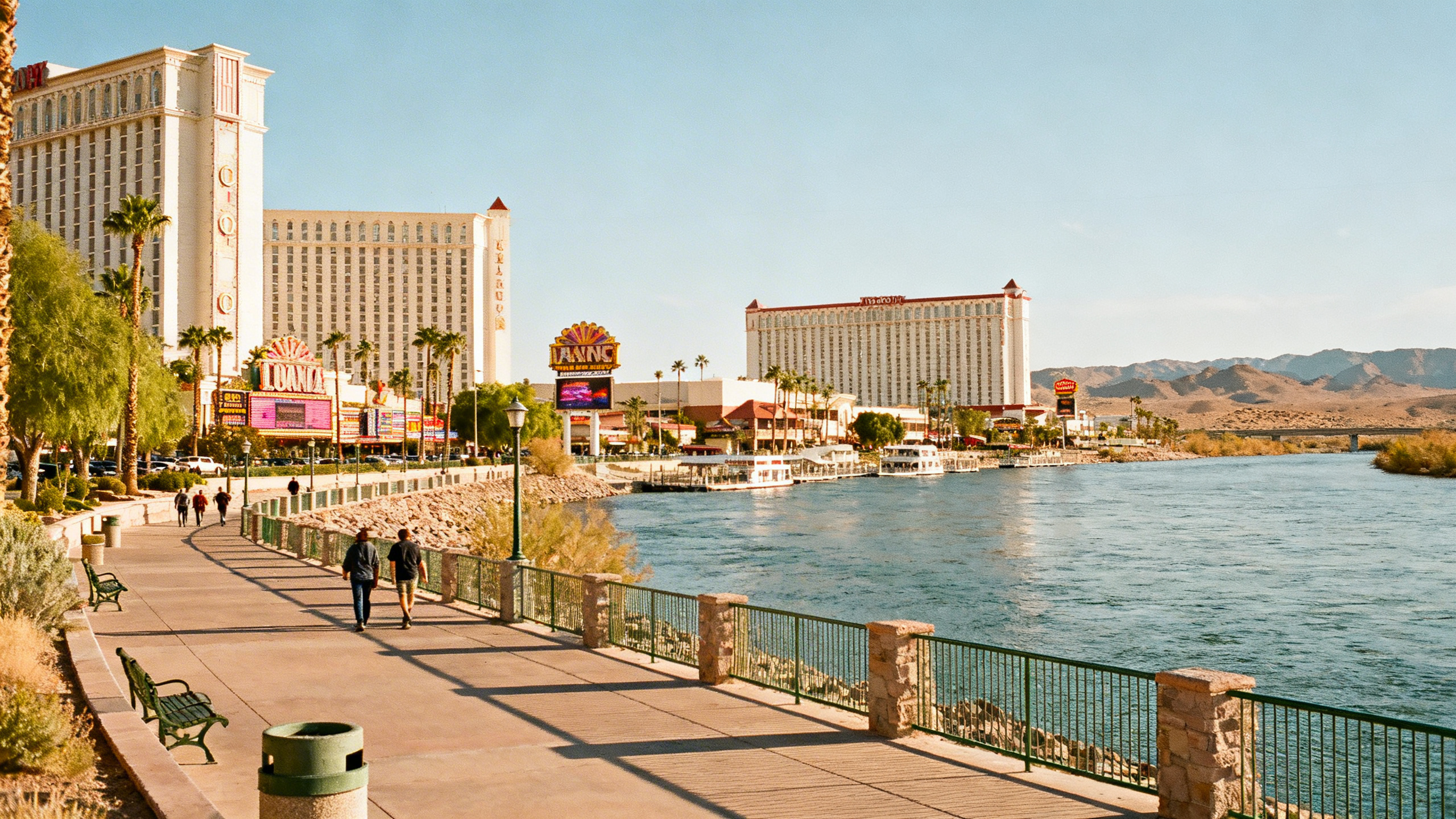 The Colorado River waterfront and modest casino hotels under a clear sky in the desert town of Laughlin, Nevada
