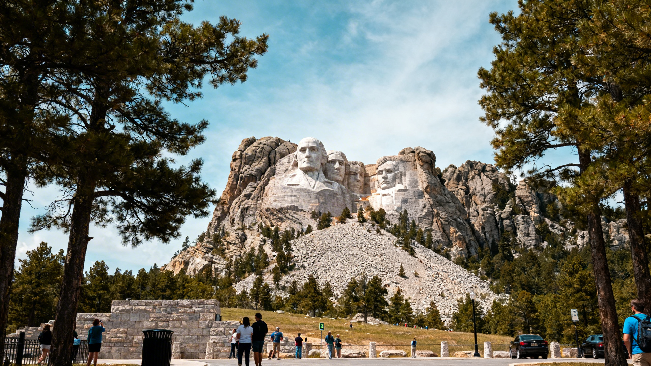 The massive mountain carving of Crazy Horse in progress, framed by pine trees and open skies in the Black Hills
