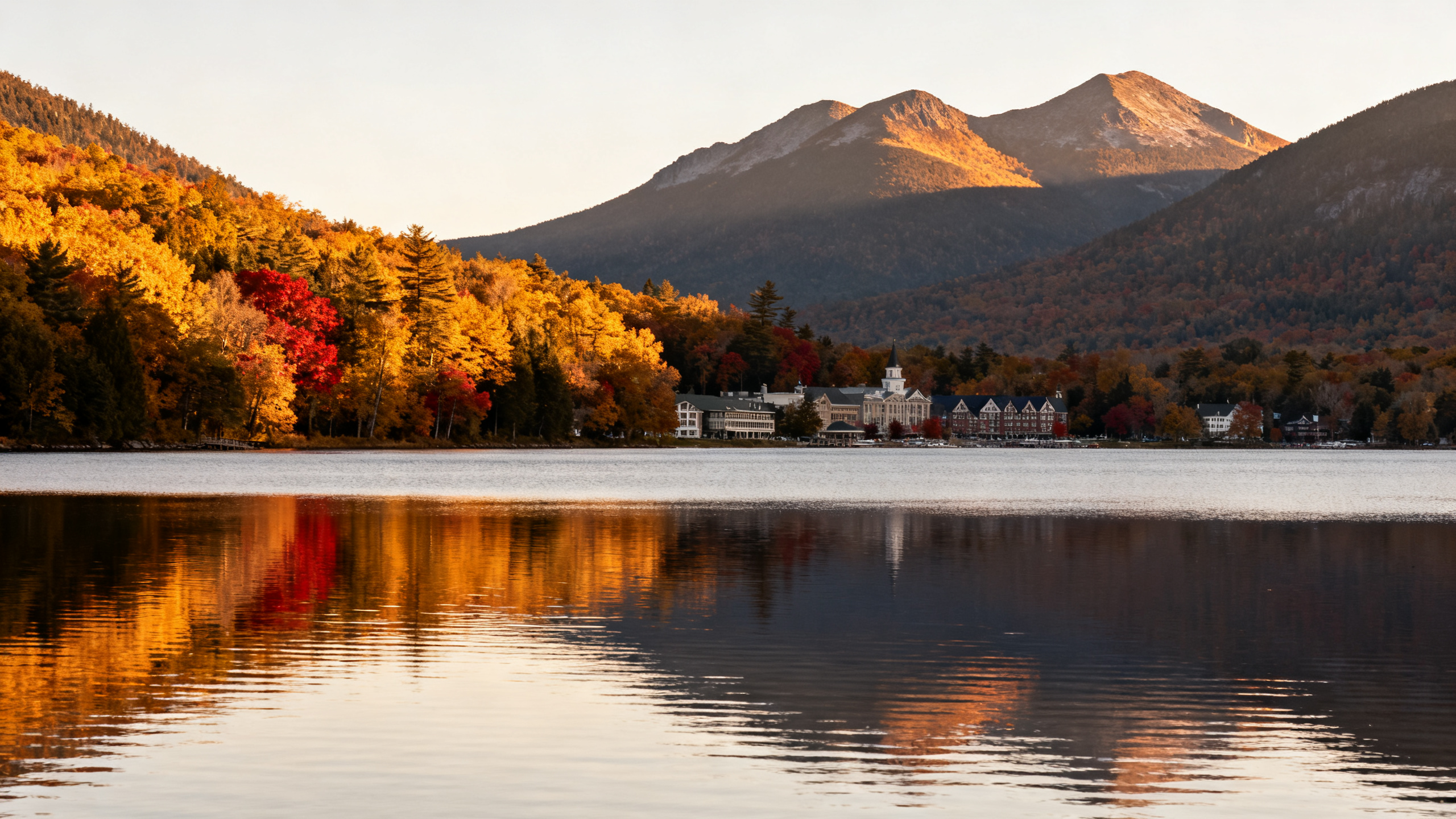 Forest-fringed waters of Lake Placid with Adirondack Mountains in the background on a crisp autumn day.