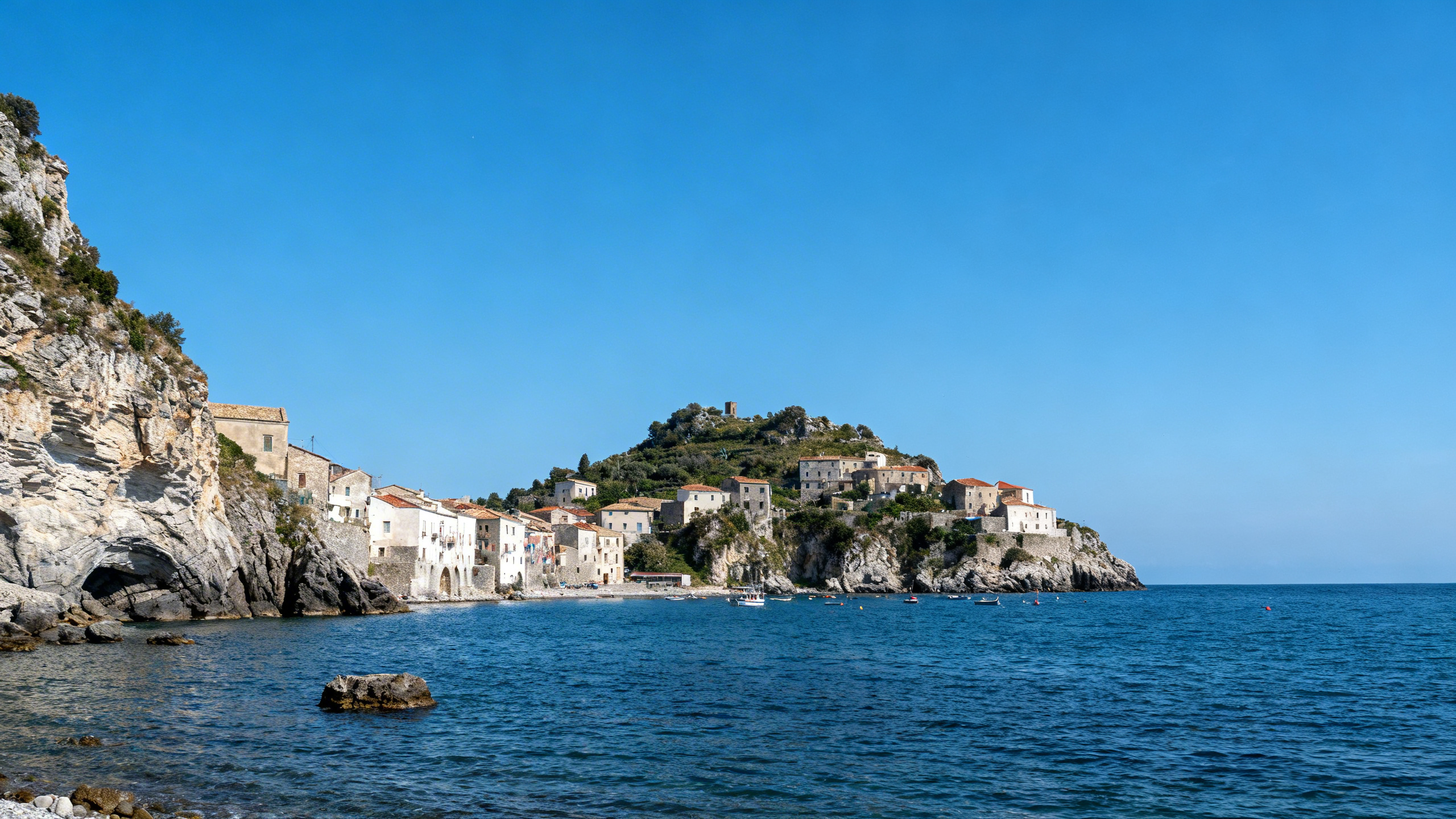 Rugged cliffs and old-fashioned fishing villages dot the dramatic coastline off a small island near Calabria, Southern Italy, under an azure sky